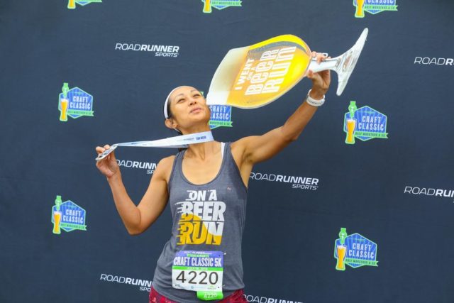 Craft Classic female runner with the photo frame prop and showcasing her finisher medal